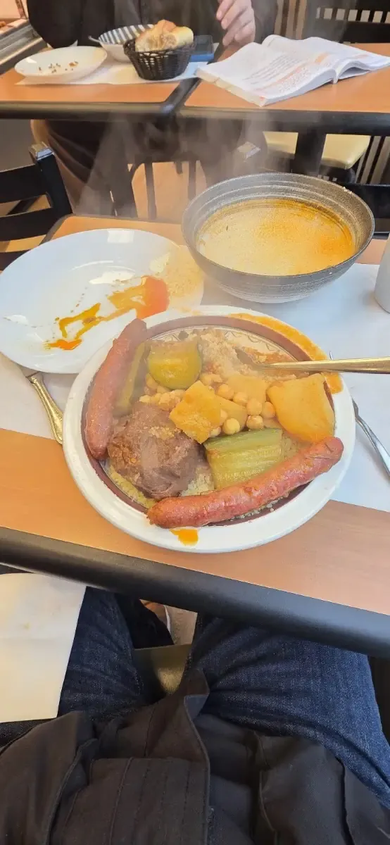 Assiette de couscous : légumes, pois chiches, merguez et bol de bouillon.