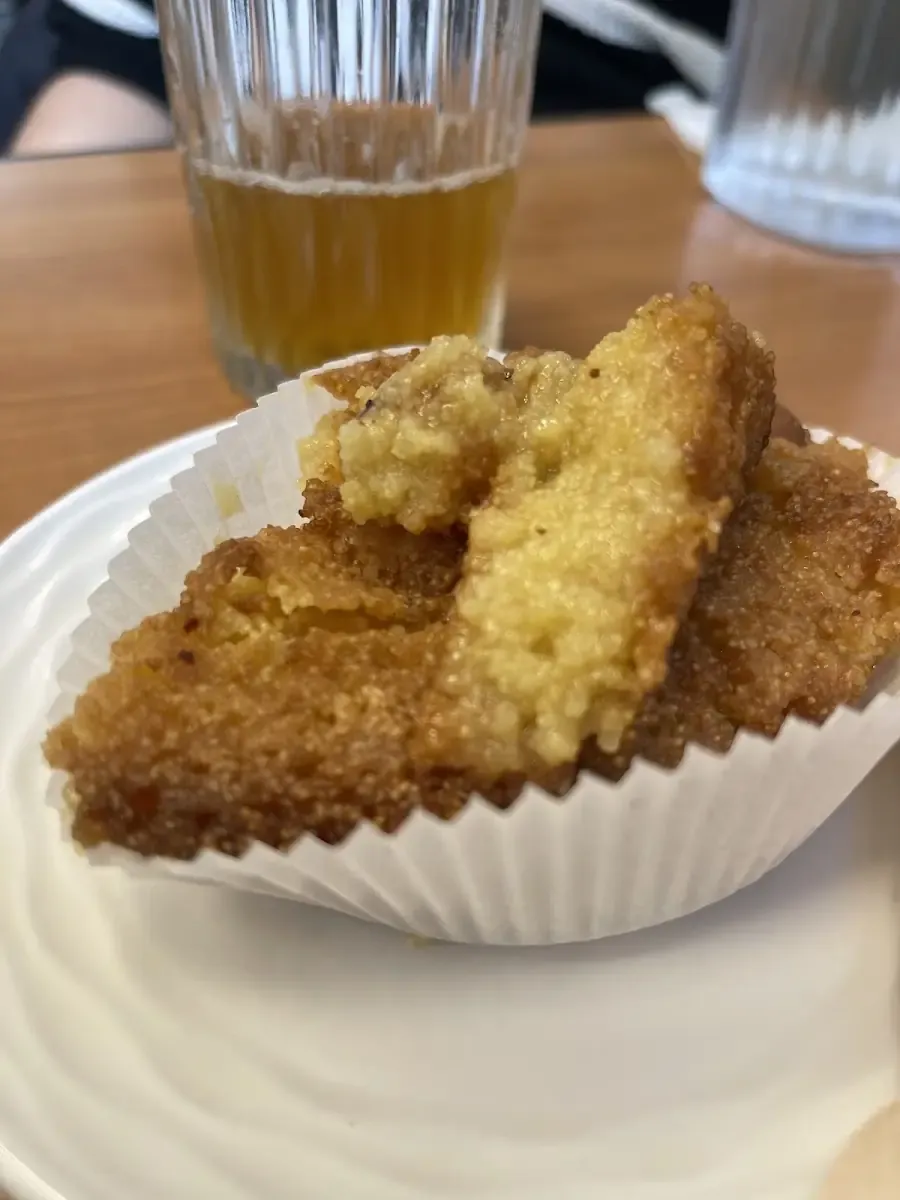 Beignet doré frit à la commande, servi dans sa caissette avec un verre de thé.